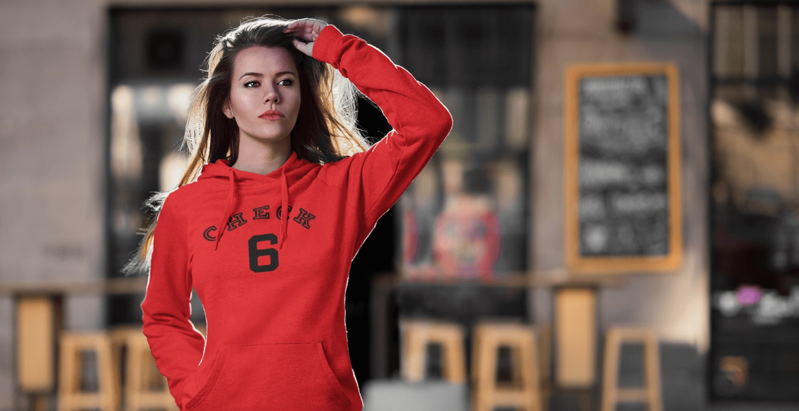 Check Your Six - Unisex Hoodie/Red on woman standing on a sidewalk in front of a sidewalk restaurant